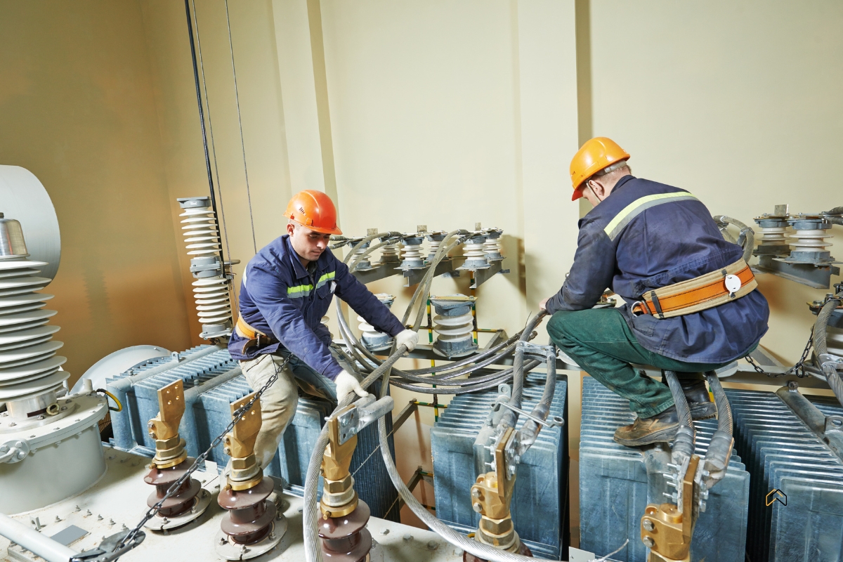 Elektrycy montujący przewody w stacji transformatorowej wysokiego napięcia