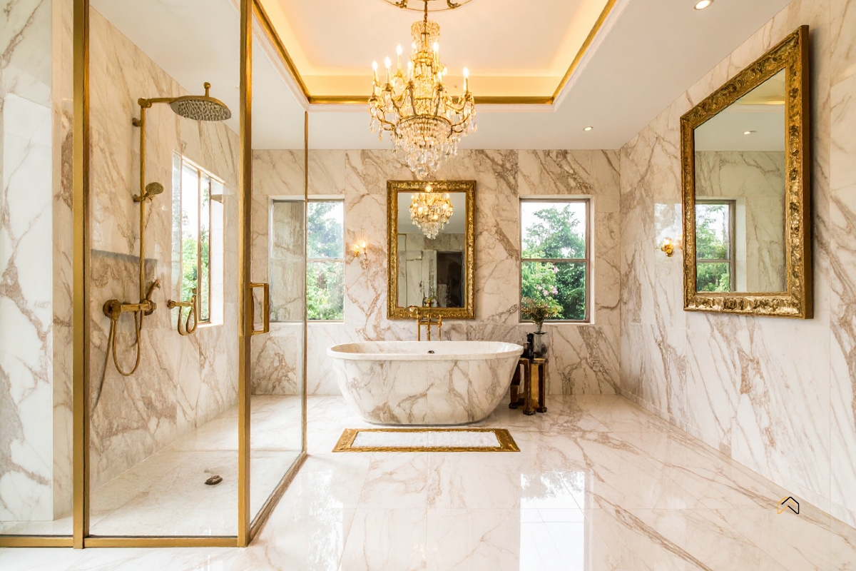 Ekskluzywna łazienka z marmurowymi ścianami — instalacje sanitarne, wolnostojąca wanna, prysznic i złota armatura