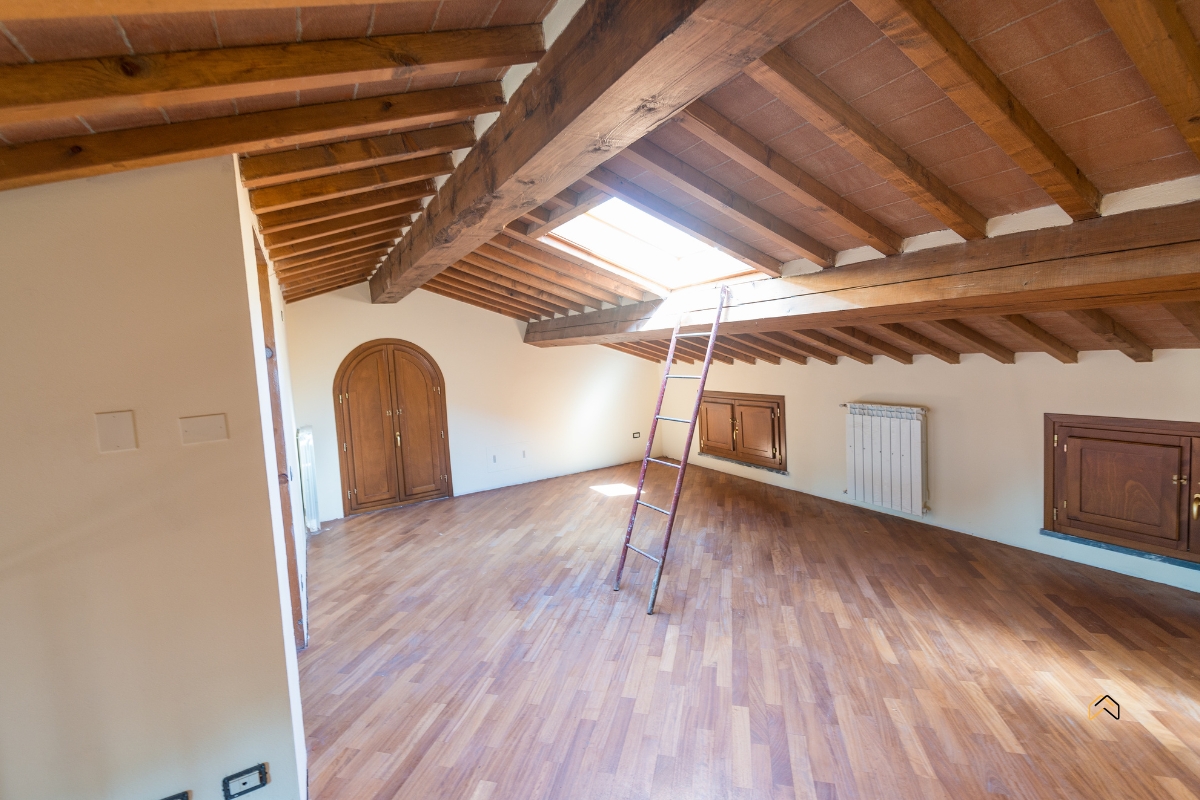 Surowe poddasze z drewnianymi belkami i oknem dachowym do adaptacji